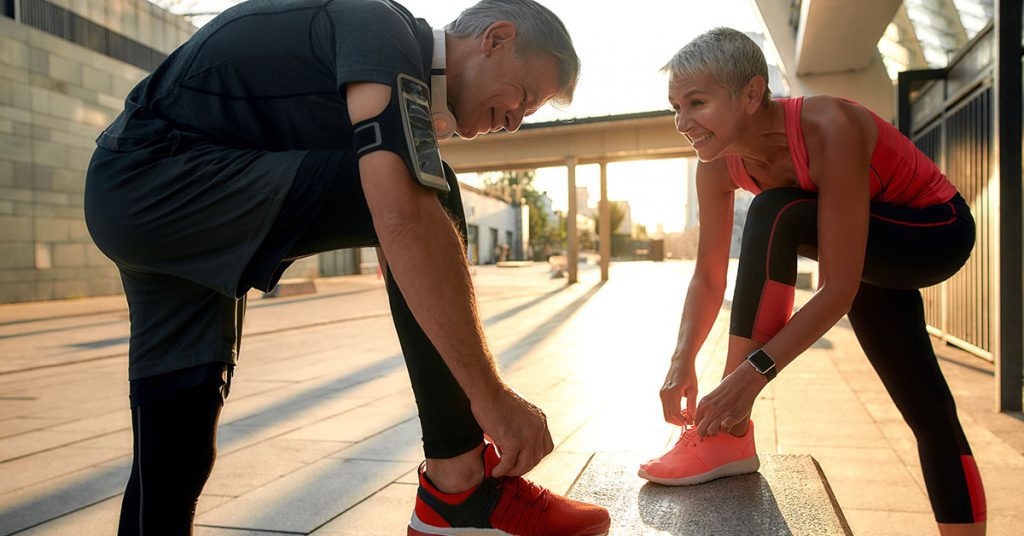 Healthy family. Active middle-aged couple in sports clothing tying shoelaces before jogging outdoors. Fit, fitness, exercise. Healthy lifestyle concept. Exercising together; blog: Safe Fitness Tips for Kidney Patients