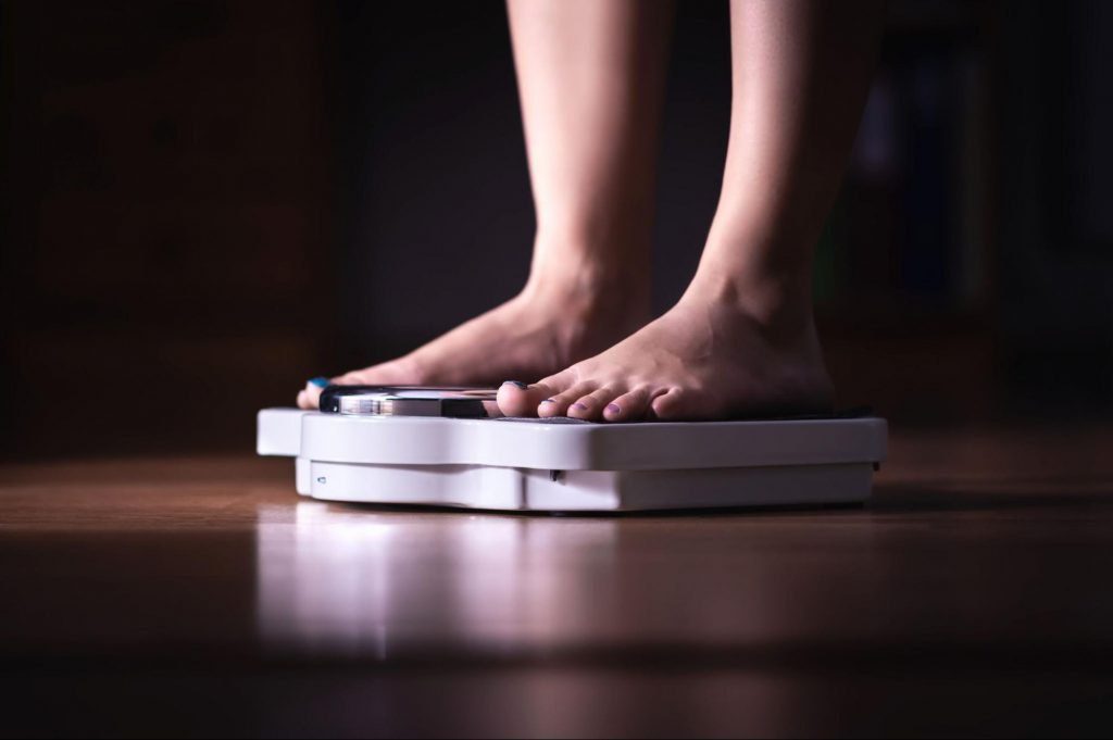 a person standing on a scale to represent Obesity and Kidney Disease